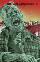 Comic book cover of "The Walking Dead Deluxe," featuring a zombie in a plaid shirt in front of a gas station.