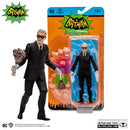 A Professor Strange action figure standing next to a sealed action figure. Both figures wear black suits and spectacles. One is holding a weapon, the packaging is bright orange and green.
