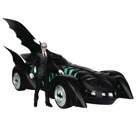 Black Batmobile toy with a gray-haired man in a black suit standing next to it.