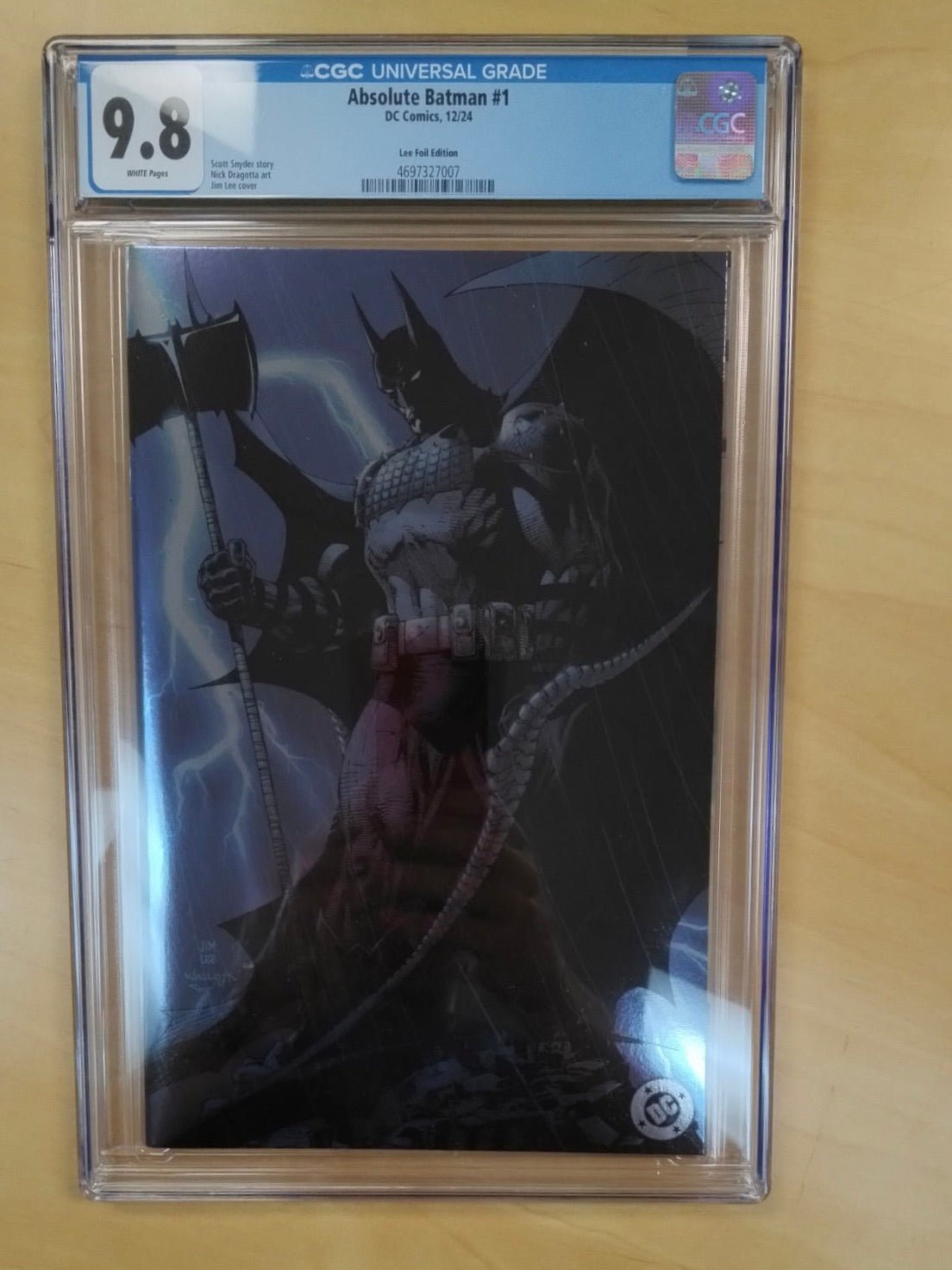 Comic book 'Absolute Batman #1' with CGC grading label on a wooden surface