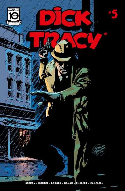 Comic book cover featuring Dick Tracy crouched in the rain, holding a gun. He wears a tan hat and trench coat. Red lettering for the title and issue number. The Mad Cave logo is in the upper left corner.
