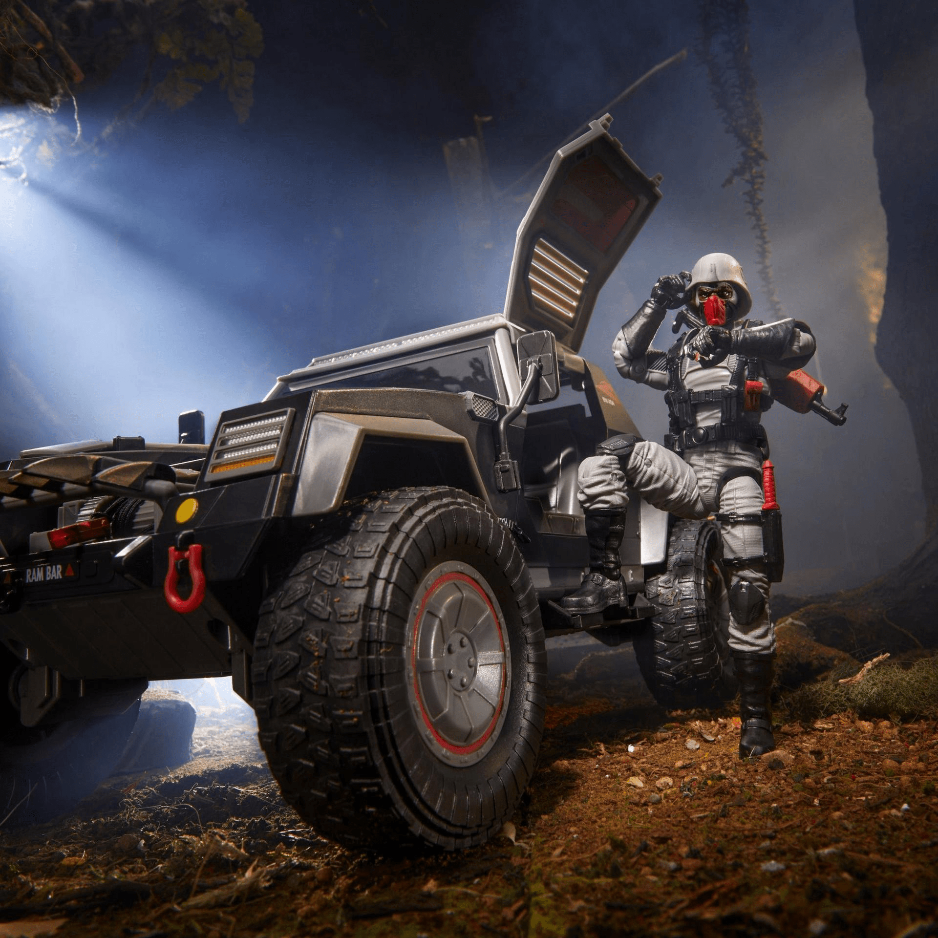 Action figure in military attire posed with off-road vehicle in a forest.