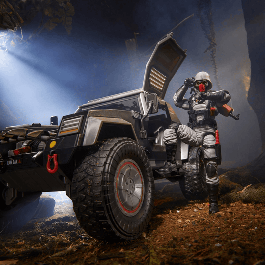 Action figure in military attire posed with off-road vehicle in a forest.