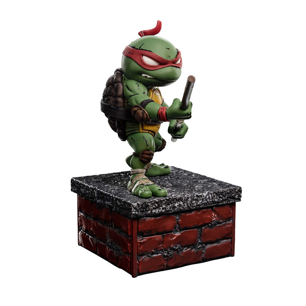 Raphael Teenage Mutant Ninja Turtle figure stands on a brick and concrete-looking base, holding sai sticks.