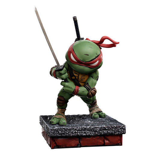 A figurine of Raphael from the Teenage Mutant Ninja Turtles, wielding a sword, standing on a brick and concrete base.