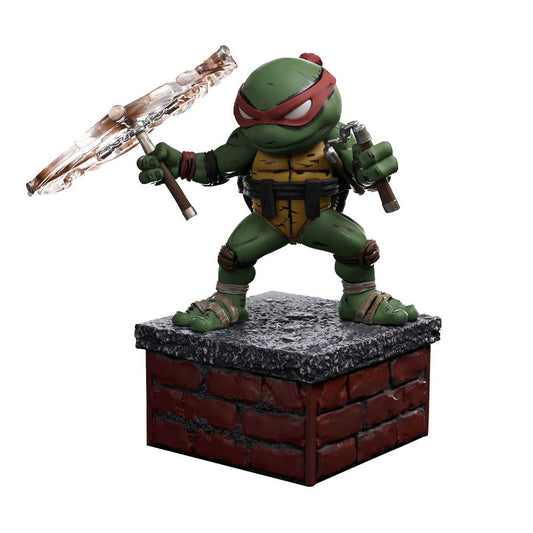 Action figure of Raphael from Teenage Mutant Ninja Turtles standing on a brick and gray concrete base holding sais.